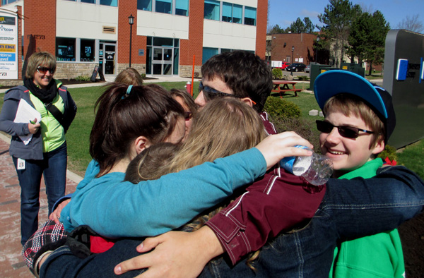 3 photos show the students gathering together into a hug that includes them all.